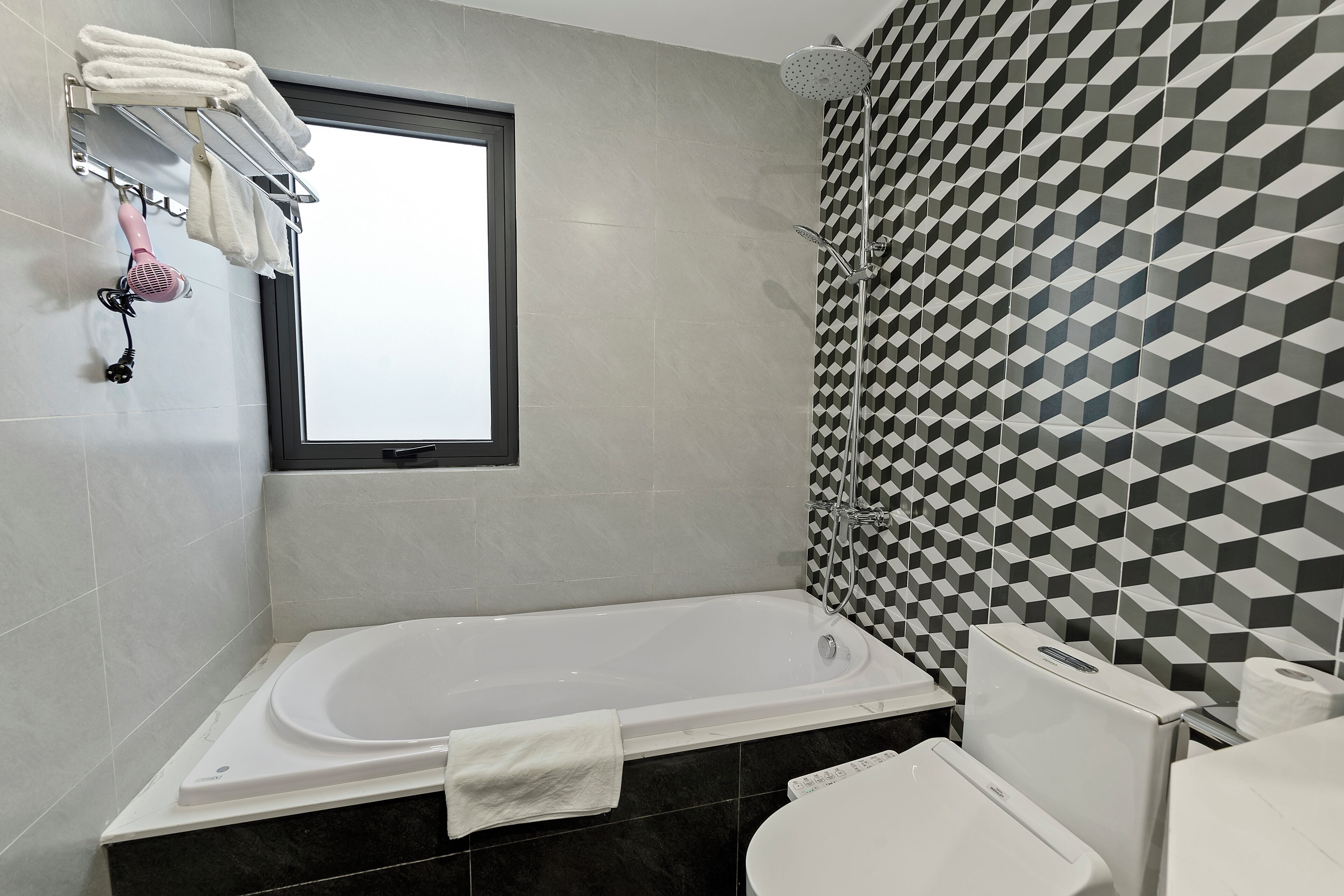 Een moderne badkamer met een bad, toilet en douche.