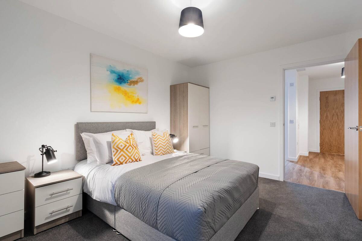 Un dormitorio moderno con cama, mesitas de noche, lámpara, un cuadro y armario.