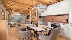 A modern kitchen with white cabinets, a wooden ceiling, and a dining area with a table and chairs. - Private Stone Villa with heated pool, Near Opatija (Ičići)