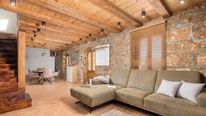 A cozy living area with a wooden ceiling, stone walls, and a modern sofa. - Private Stone Villa with heated pool, Near Opatija (Ičići)