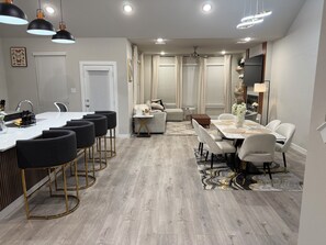 A modern kitchen with a central island, black bar stools, and pendant lighting. - Quiet Red Oak Getaway, Pet Friendly and Gameroom (Red Oak)