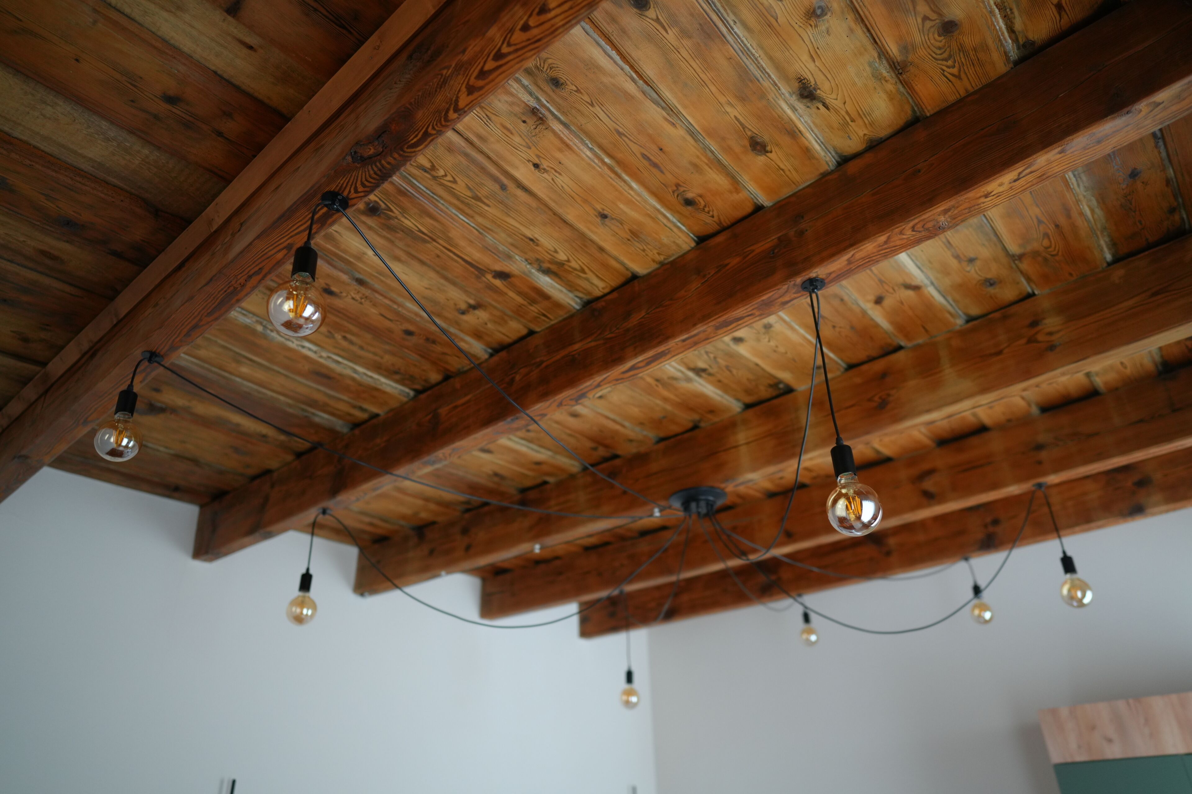 Techo con vigas de madera a la vista y lámparas colgantes.
