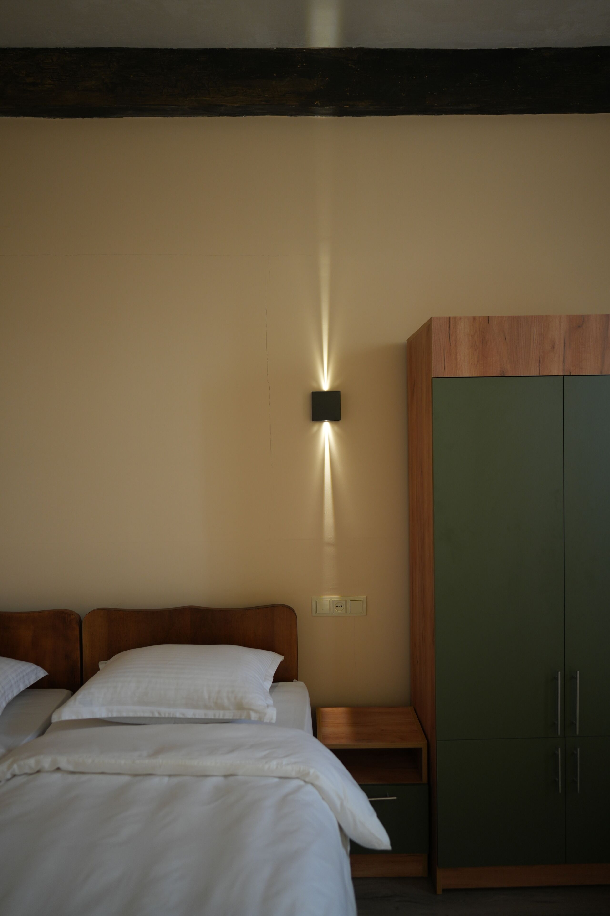 Un dormitorio con cama, mesita de noche, luz empotrada en la pared y armario.
