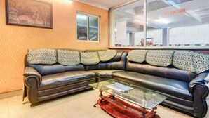 A modern living room with a black leather sofa, a glass coffee table, and a framed picture on the wall. - Sri ganesh Swati residency  (Visakhapatnam)