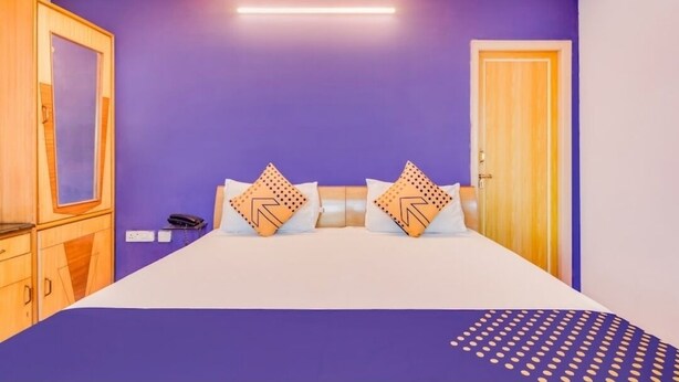 A bedroom with a bed, two pillows, a bedside table, a phone, and a door. - Sri ganesh Swati residency  (Visakhapatnam)