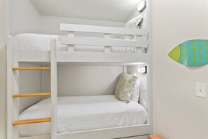 Un lit superposé avec une t ête de lit blanche, une échelle en bois et un lit simple en dessous.