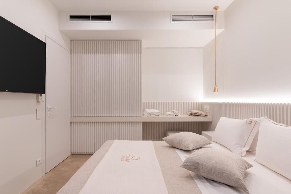 A modern bedroom with a bed, bedside table, and a mounted TV.