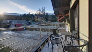 A balcony with outdoor seating, a view of a railway track, and a building in the background. - RentPlanet - Apartamenty przy Wyciągu (Szklarska Poręba)