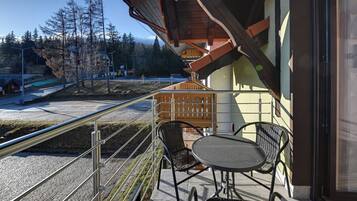 A balcony with a table and chairs, overlooking a snowy landscape and a road with vehicles.