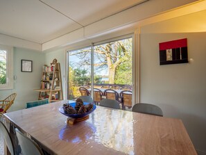 A dining area with a large table, chairs, a bowl of pinecones, a bookshelf, and a view of the outdoors. - Family house by Lake Aureilhan for 10 people (Aureilhan)