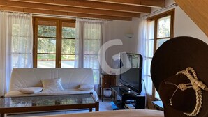 Una habitación acogedora con sofá, una mesita de cristal, televisor y un adorno sobre un pedestal.
