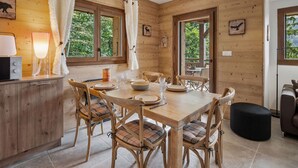 A wooden interior with a dining table set for six, surrounded by plaid chairs. - Apartment 4 pers, balcony, covered parking (Cohennoz)