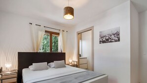 A bedroom with a large bed, a bedside table with a lamp, a window with curtains, and a framed picture on the wall. - Apartment 4 pers, balcony, covered parking (Cohennoz)
