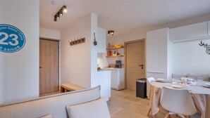 Een modern, goed verlicht appartement met een eethoek, kitchenette en een woongedeelte met een bank en kussens.
