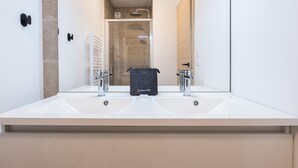 Een moderne badkamer met een grote spiegel, twee wasbakken en een douche.