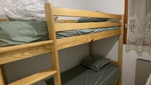 Una cama litera con ropa de cama verde y una escalera.