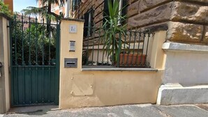 A gated entrance with a mailbox and a small window, surrounded by a stone wall and a metal fence. - Raffy in Rome (Rome)