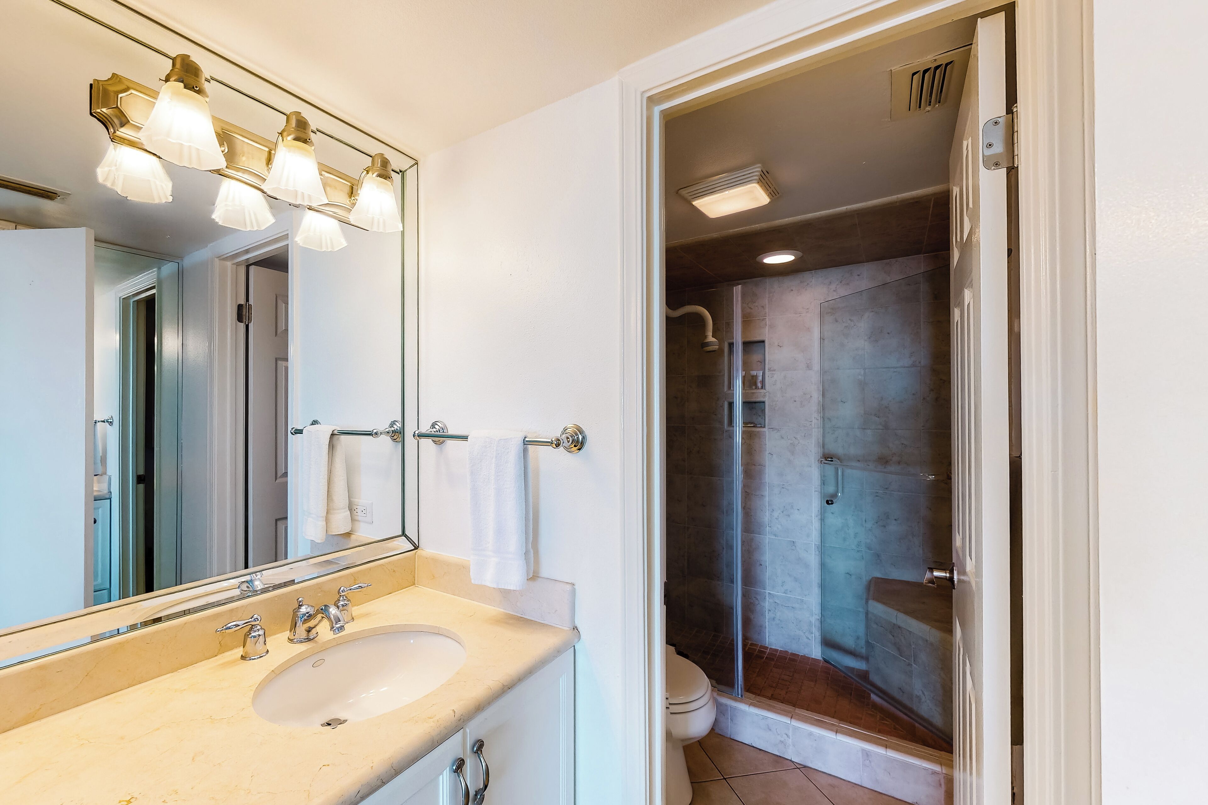 A bathroom with a sink, mirror, and shower.