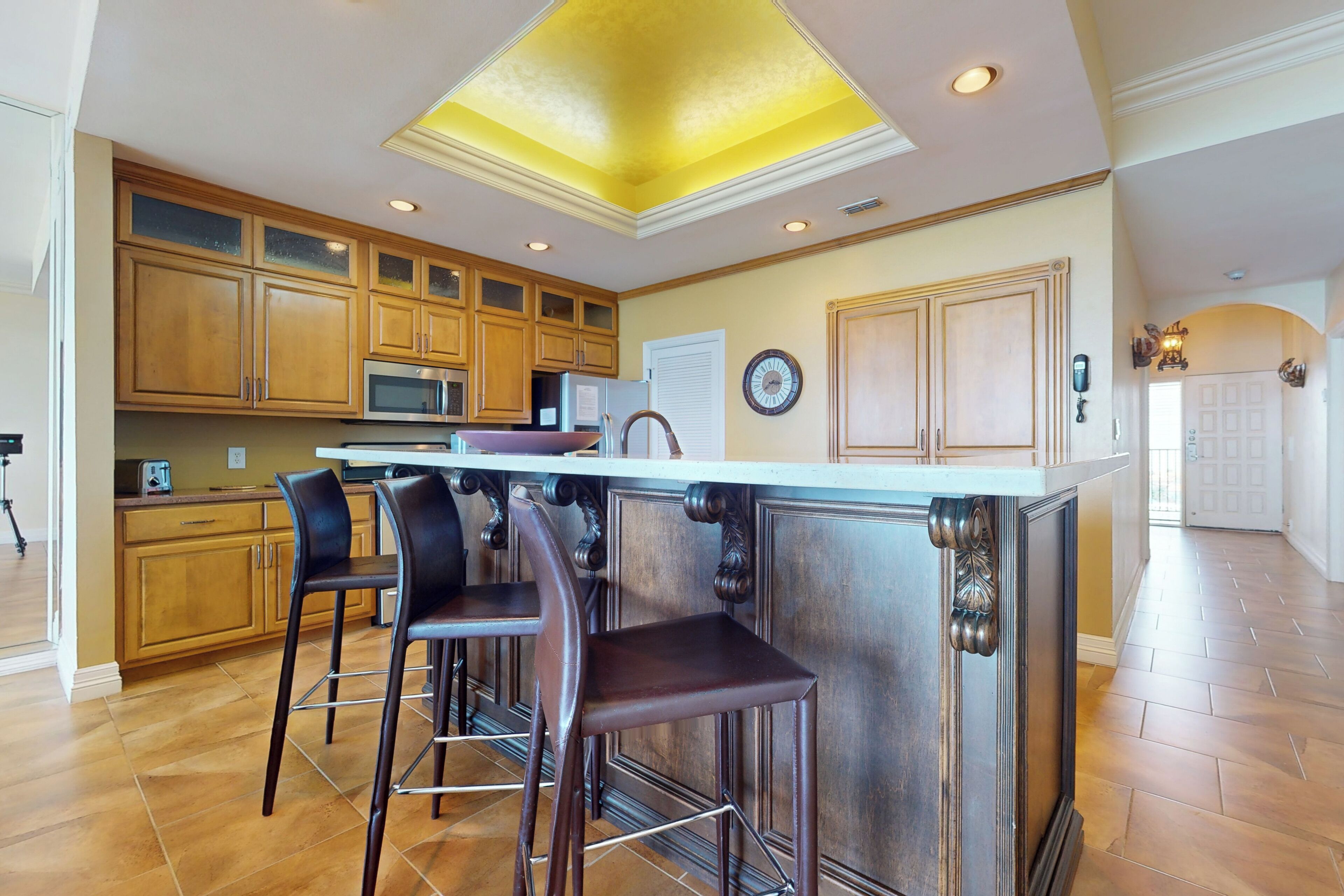 Una cocina amplia con armarios de madera, una isla central con taburetes de bar y un diseño de techo moderno.