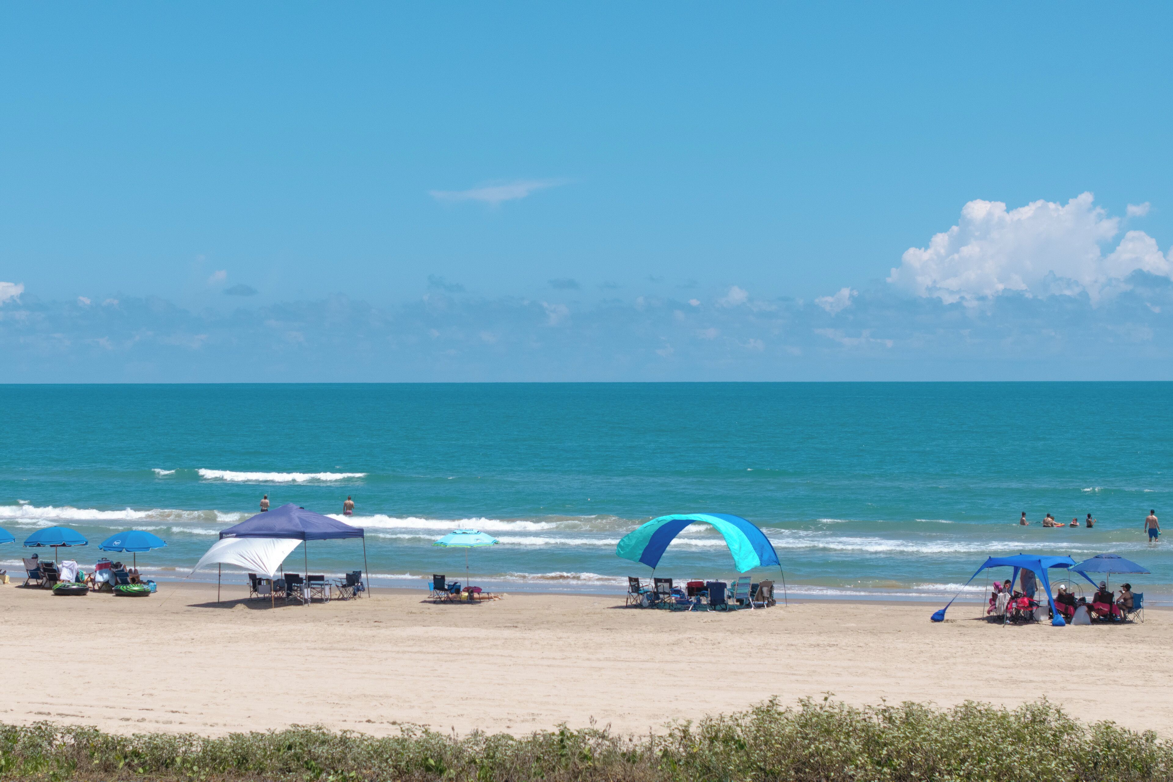 A beach with umbrellas and chairs, a clear sky, and the ocean.