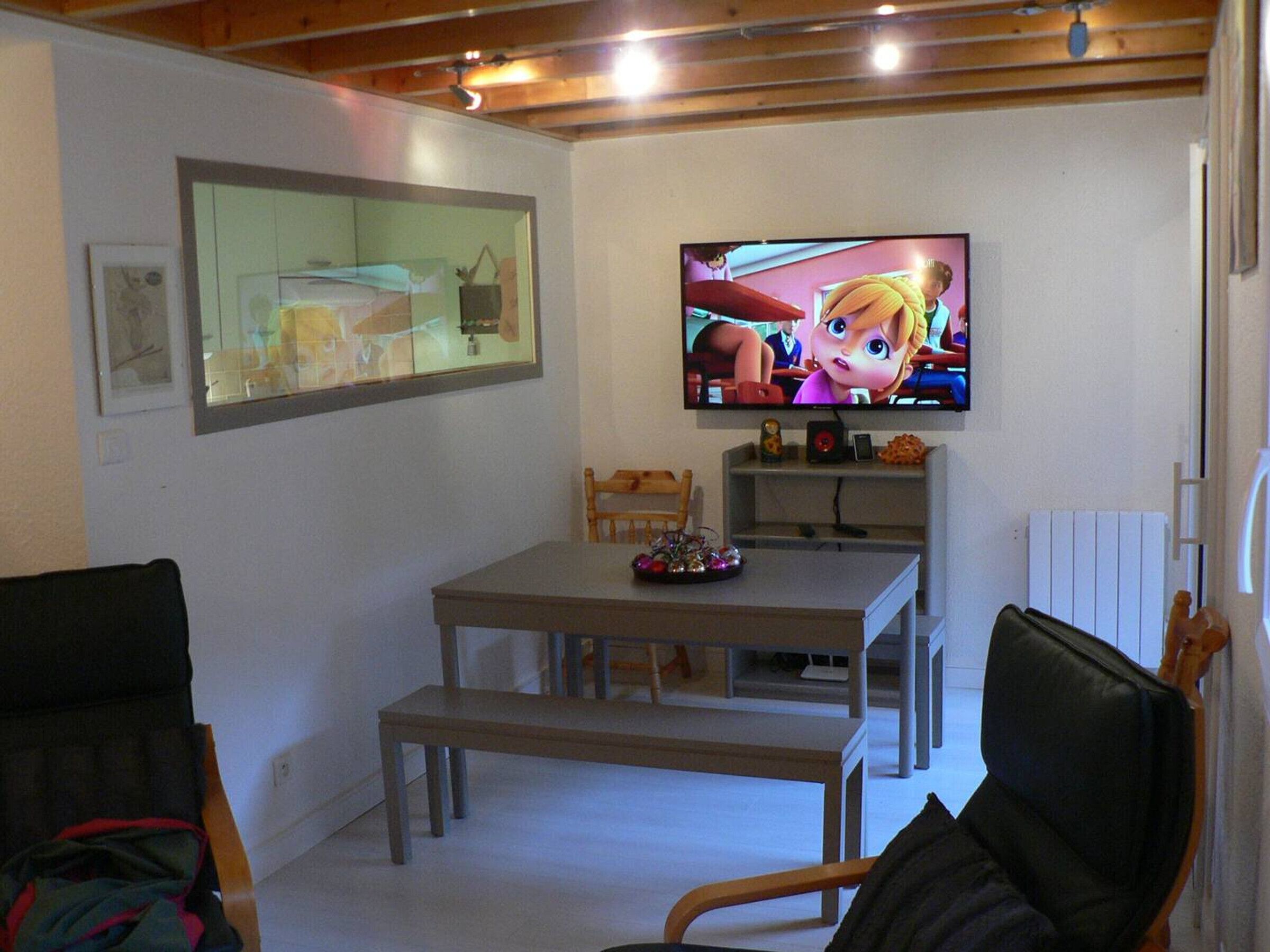 Una sala de estar con televisión, una mesa de comedor y dos sillas.