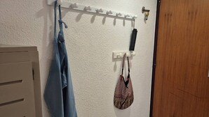 Un pasillo con un perchero, una puerta de madera y una pared blanca.