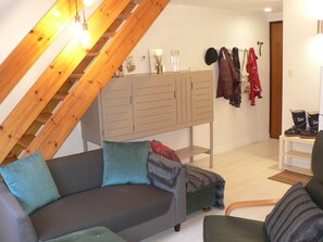 A room with a sloped ceiling, a sofa with cushions, a cabinet, and a coat rack with jackets. - Bright duplex for 6 near center with balcony (Cauterets)