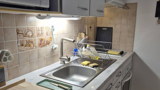 Una cocina con un lavamanos de acero inoxidable, un escurreplatos y una tabla de cortar.