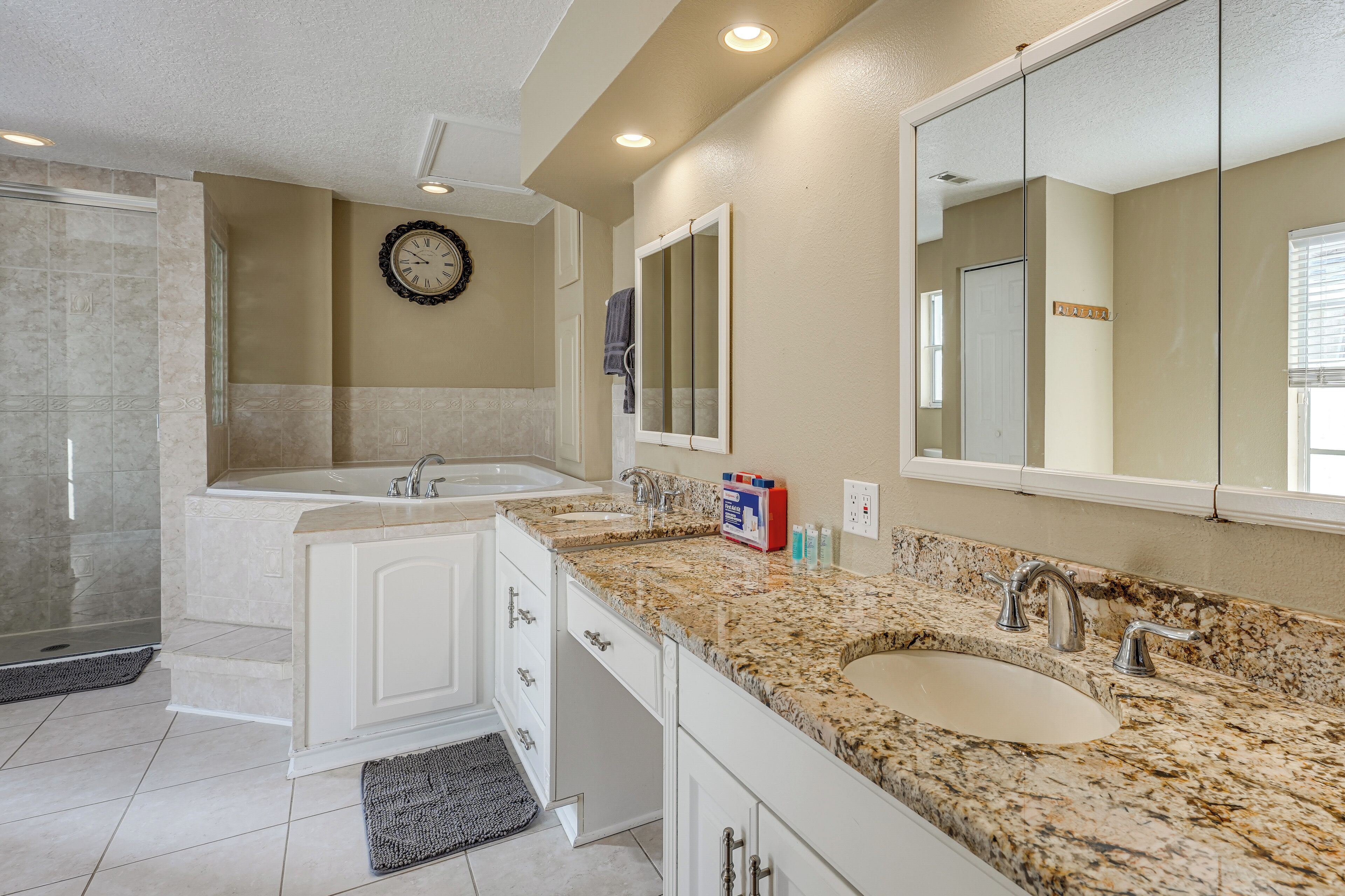 A modern bathroom with a double sink, a large mirror, and a clock on the wall.