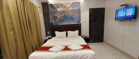 A hotel room with a large bed, a ceiling fan, a flat-screen TV, and a large window with curtains.