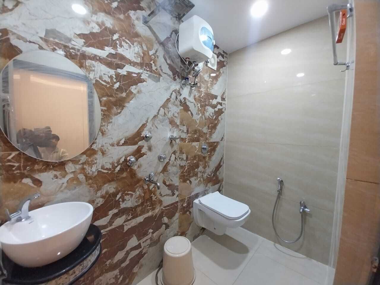 A bathroom with a marble wall, a sink, a toilet, and a shower.