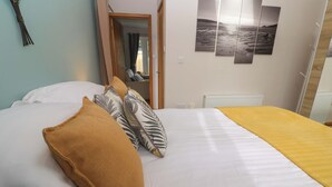 A neatly made bed with white linens and a yellow throw blanket, a brown pillow, and a decorative pillow with a leaf pattern. - Blake Lodge (Newquay)