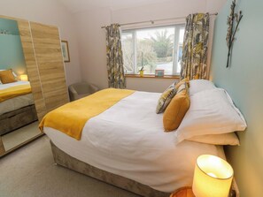 A hotel room with a bed, a chair, a wardrobe, and a window with curtains. - Blake Lodge (Newquay)