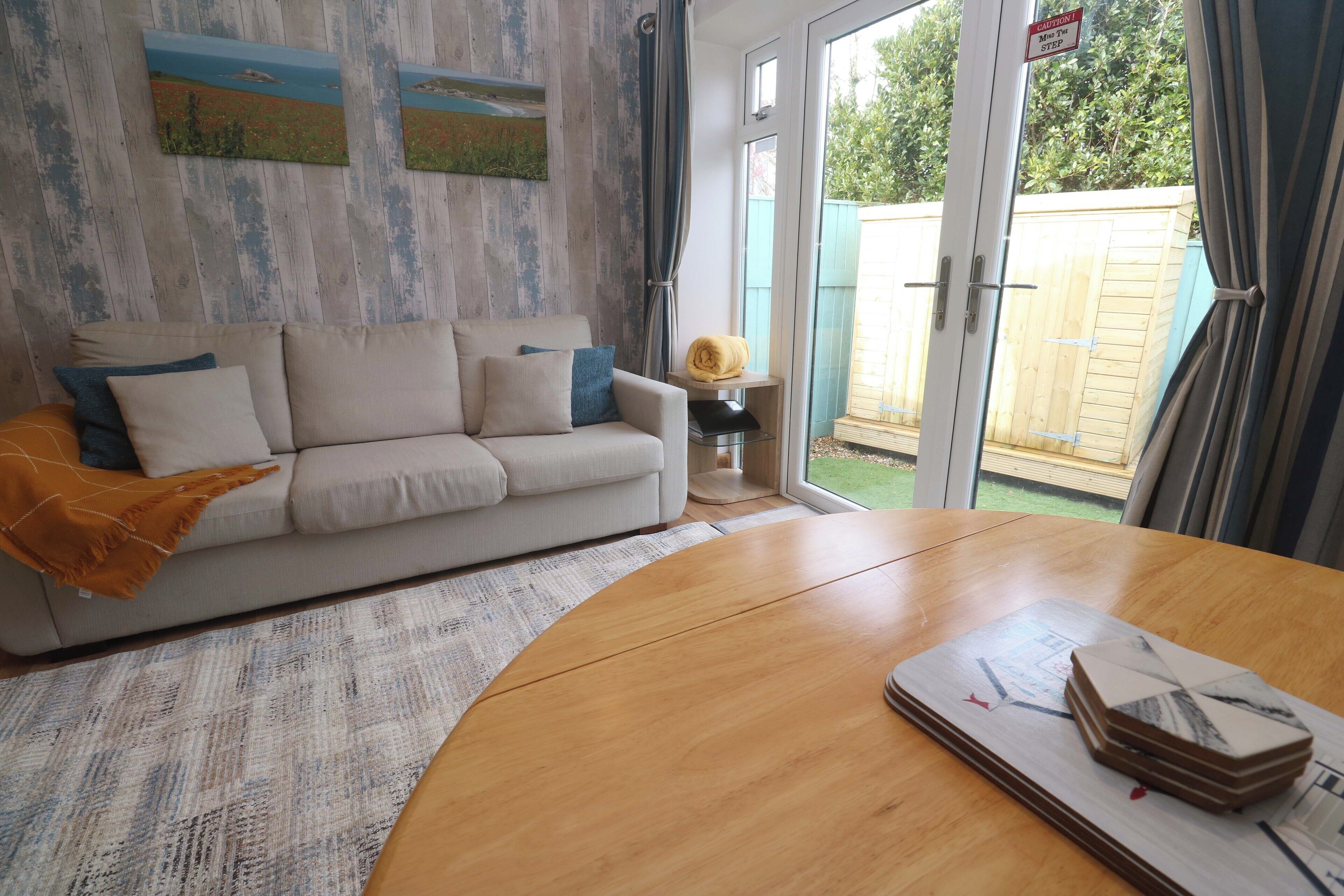 A living room with a sofa, a coffee table, and a door leading to a garden.