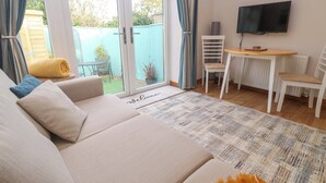 A cozy living room with a sofa, a coffee table, and a TV mounted on the wall. - Blake Lodge (Newquay)