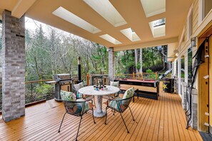 A covered outdoor deck with a wooden floor, a round table with chairs, a grill, and a pool table. - Steps to Shore: Seaside Olympia Retreat w/ Hot Tub (Olympia)