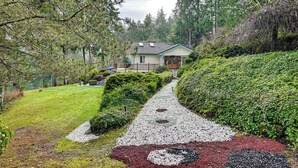 Une maison entourée d’un jardin, avec un chemin de gravier menant à l’entrée.