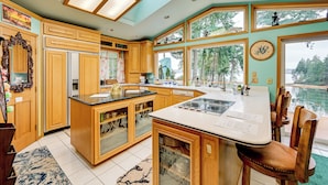 Une cuisine spacieuse avec des meubles en bois, un grand îlot central et une vue sur un lac.
