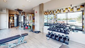 Ein Fitnessraum mit Trainingsgeräten, einer Bank und einem Dumbbell-Gestell.