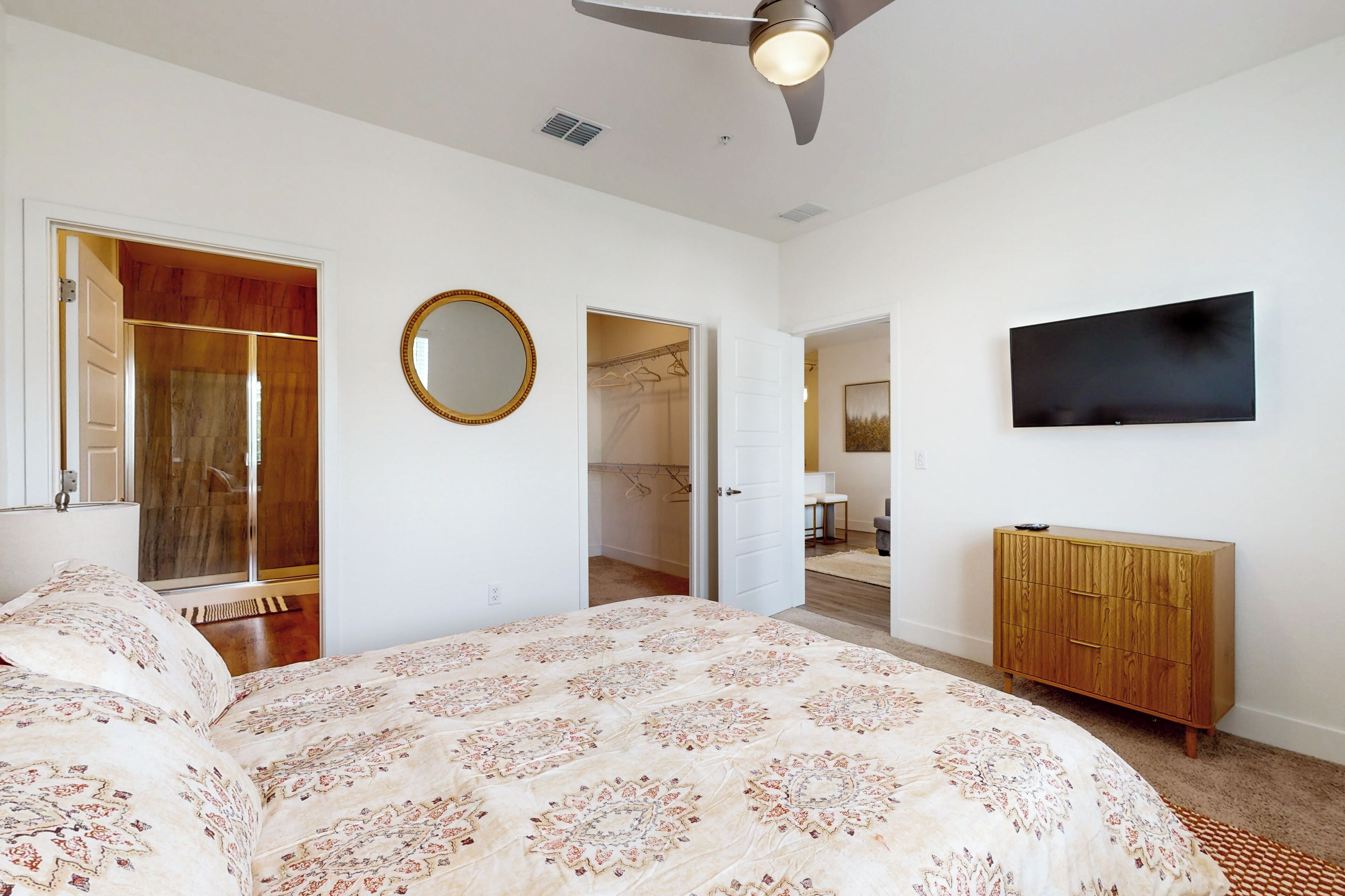 Ein Schlafzimmer mit einem großen Bett, einem Kleiderschrank, einem Spiegel und einem an der Wand befestigten Fernseher.