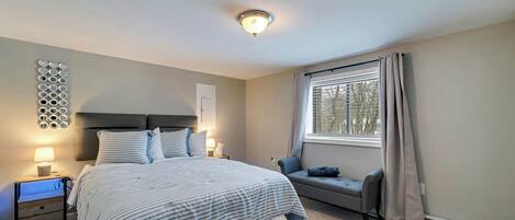 A bedroom with a bed, bedside table, lamp, and a window with curtains.