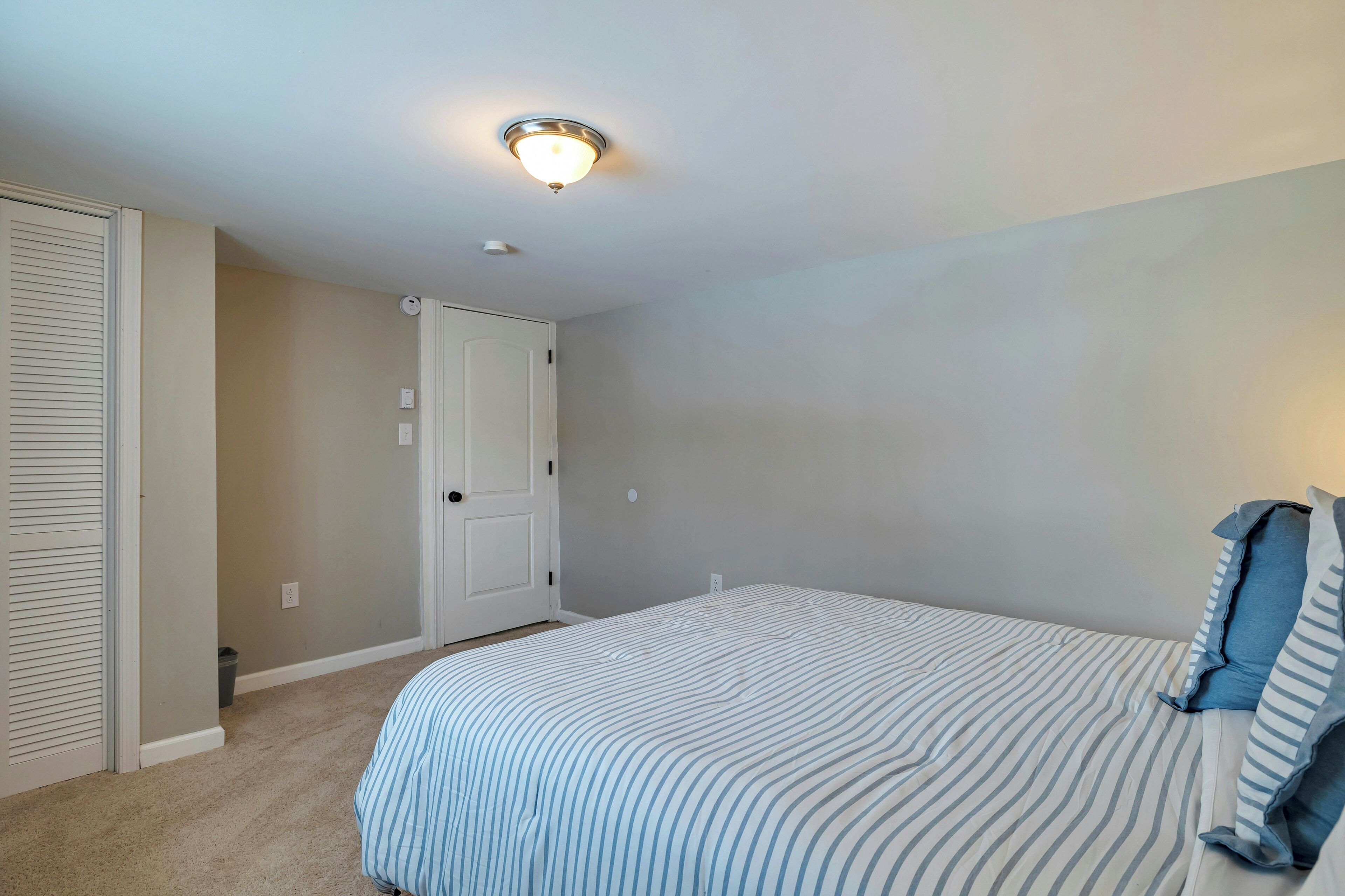 A bedroom with a bed, a closet, and a door.