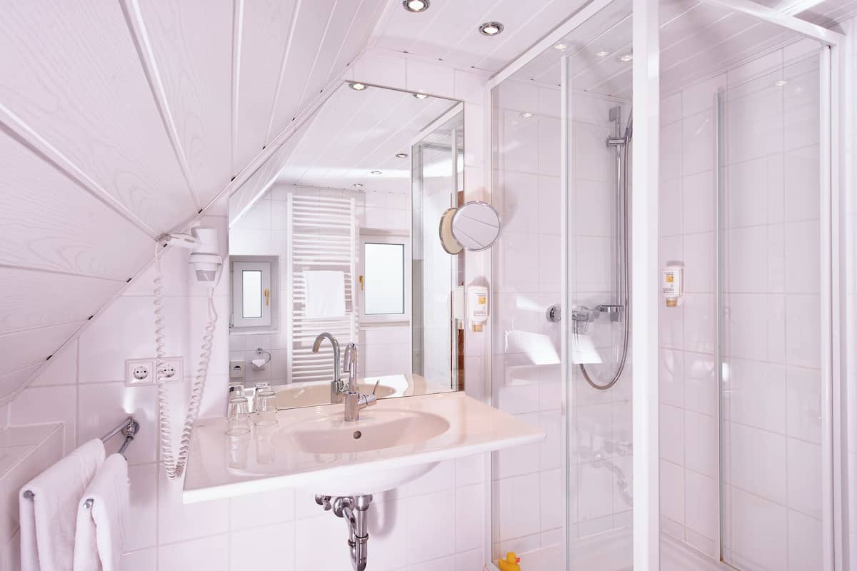 Un baño moderno con un espejo grande, un lavamanos y una ducha.