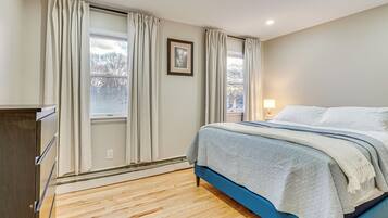 A bedroom with a bed, a dresser, and a window with curtains.