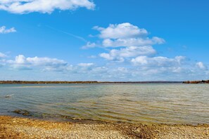 A clear view of a lake with a pebbly shore and distant land. - Lakefront 4BR w/ Stunning Views, Dock & Porch (Auburn)