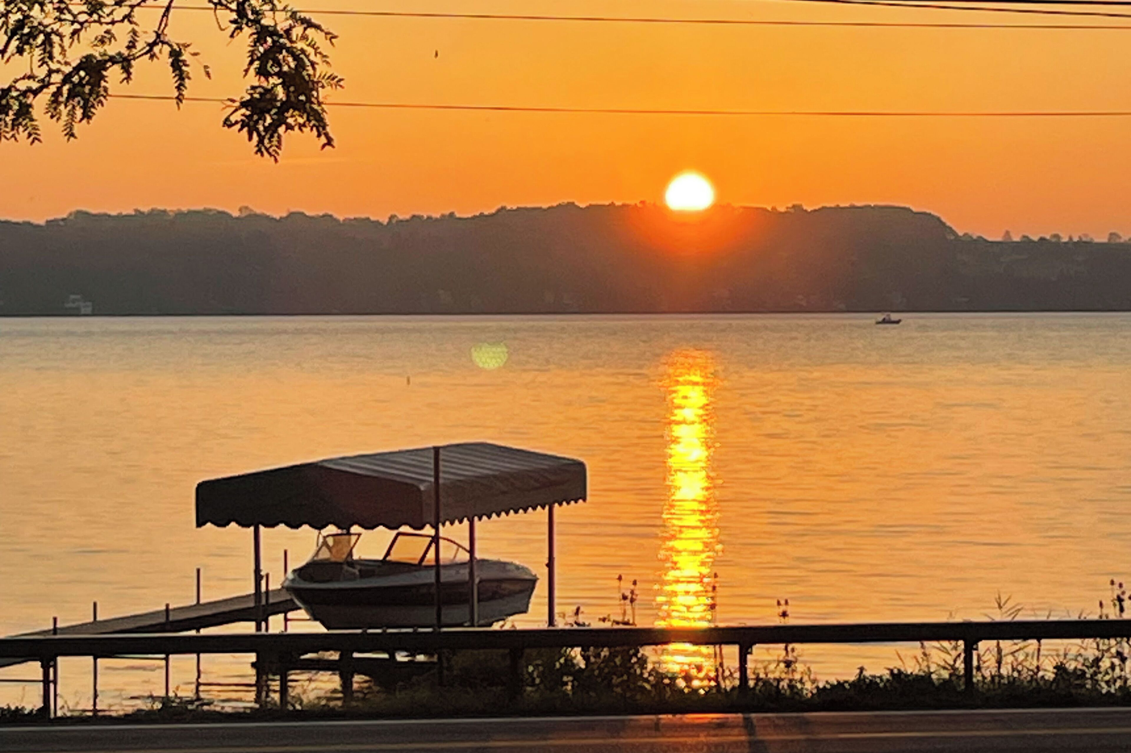 A sunset over a calm lake with a boat docked on a pier.