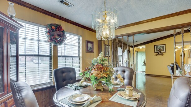 A dining room with a round table set for four, surrounded by leather chairs. A chandelier hangs from the ceiling, and a wreath is displayed on a window sill. - Pool & Large Covered Patio! Decatur Family Getaway (Decatur)