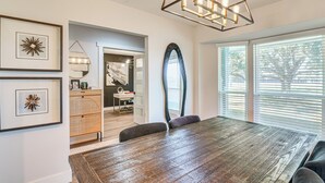 A dining area with a wooden table, framed artwork, and a modern chandelier. - Family-friendly Home on 2 Acres Near Dtwn Houston (Manvel)