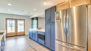 A modern kitchen with a stainless steel refrigerator, dark blue cabinets, and a wooden countertop. - Family-friendly Home on 2 Acres Near Dtwn Houston (Manvel)