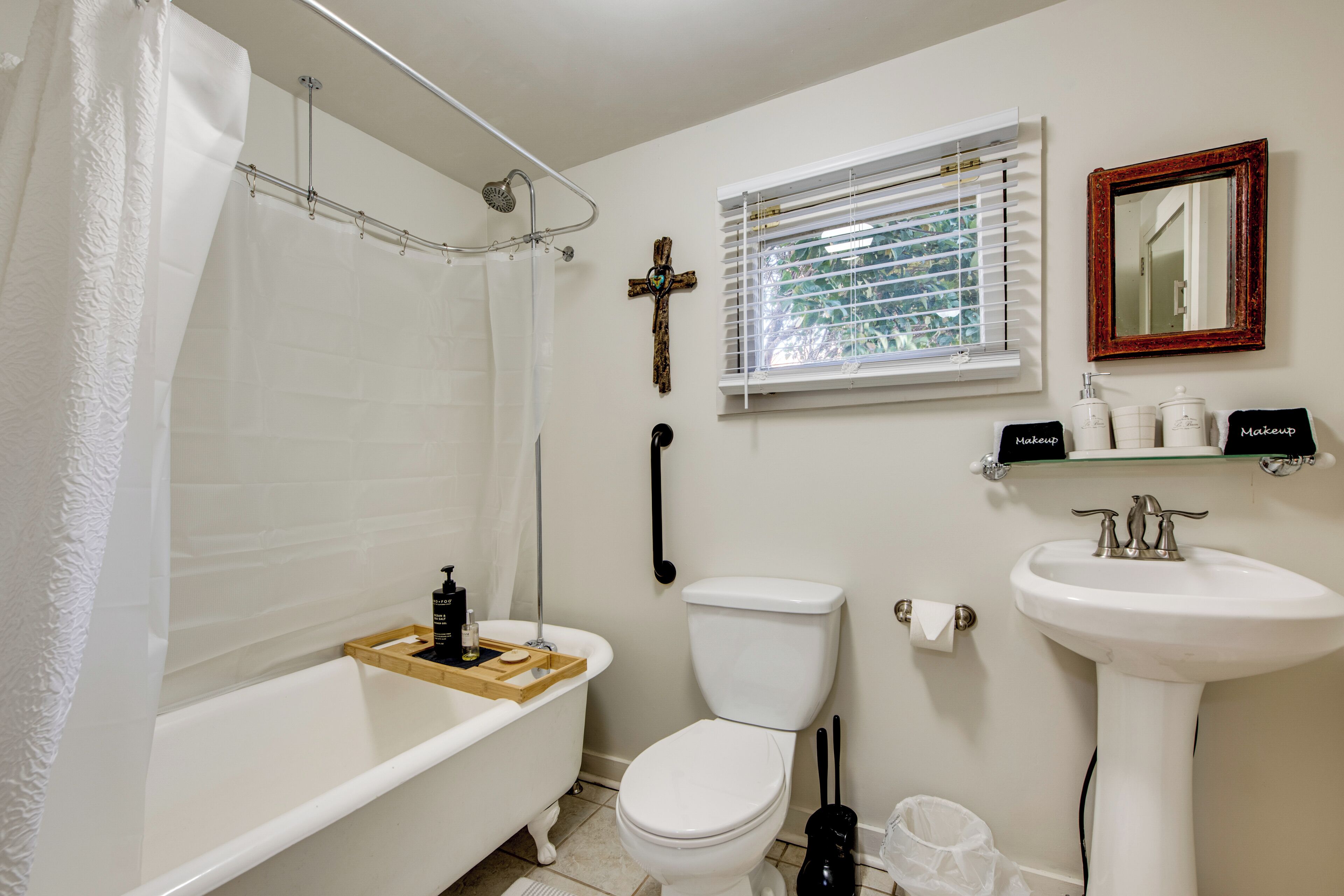 A bathroom with a bathtub, toilet, sink, and a window with blinds.